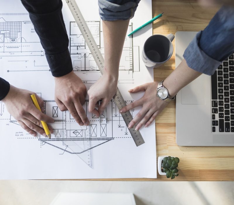 high-angle-view-worker-s-hand-working-blueprint-wooden-table-workplace