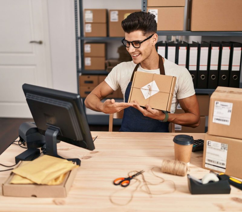 young-hispanic-man-ecommerce-business-worker-having-video-call-showing-package-office